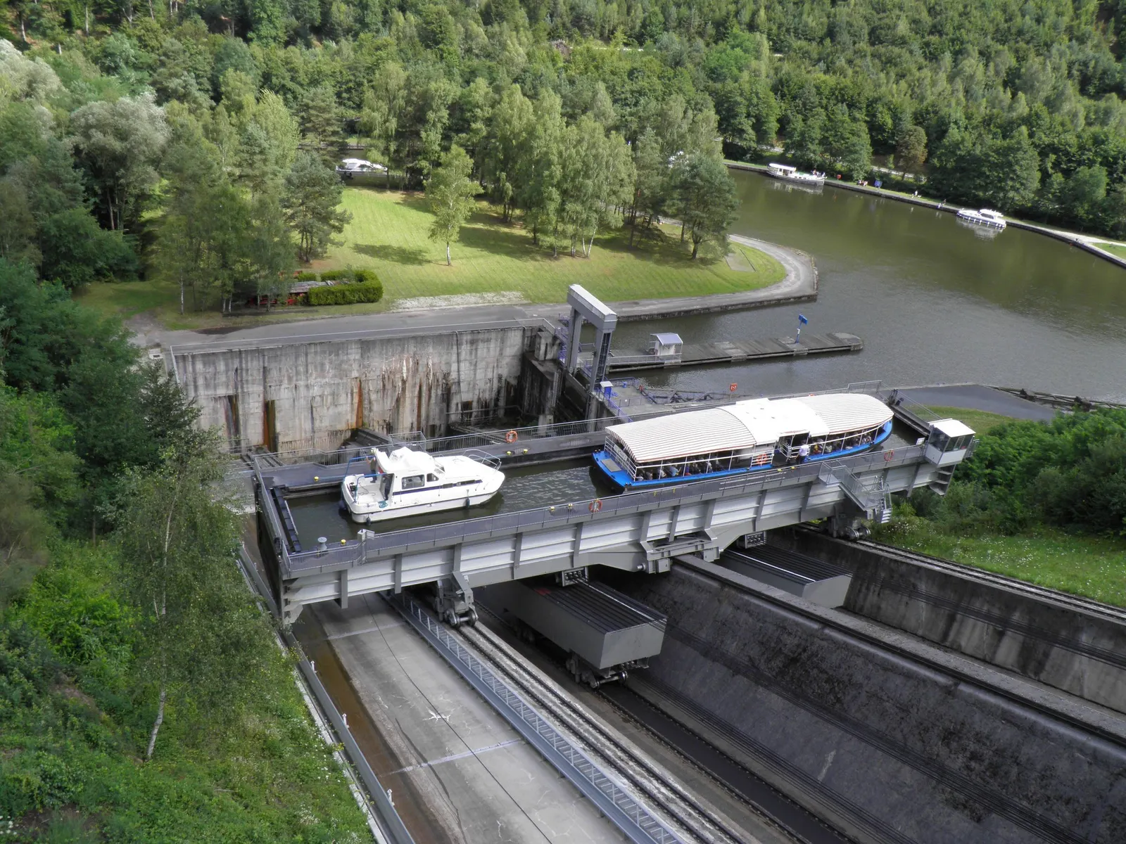 Vue plongeante sur le bac du plan incliné de Saint-Louis-Arzviller transportant deux bateaux de plaisance, au-dessus des rails et du contrepoids